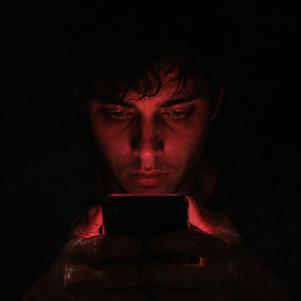 A tired man staring at a red glowing phone screen in the dark, illustrating the emotional toll of toxic texting psychology.